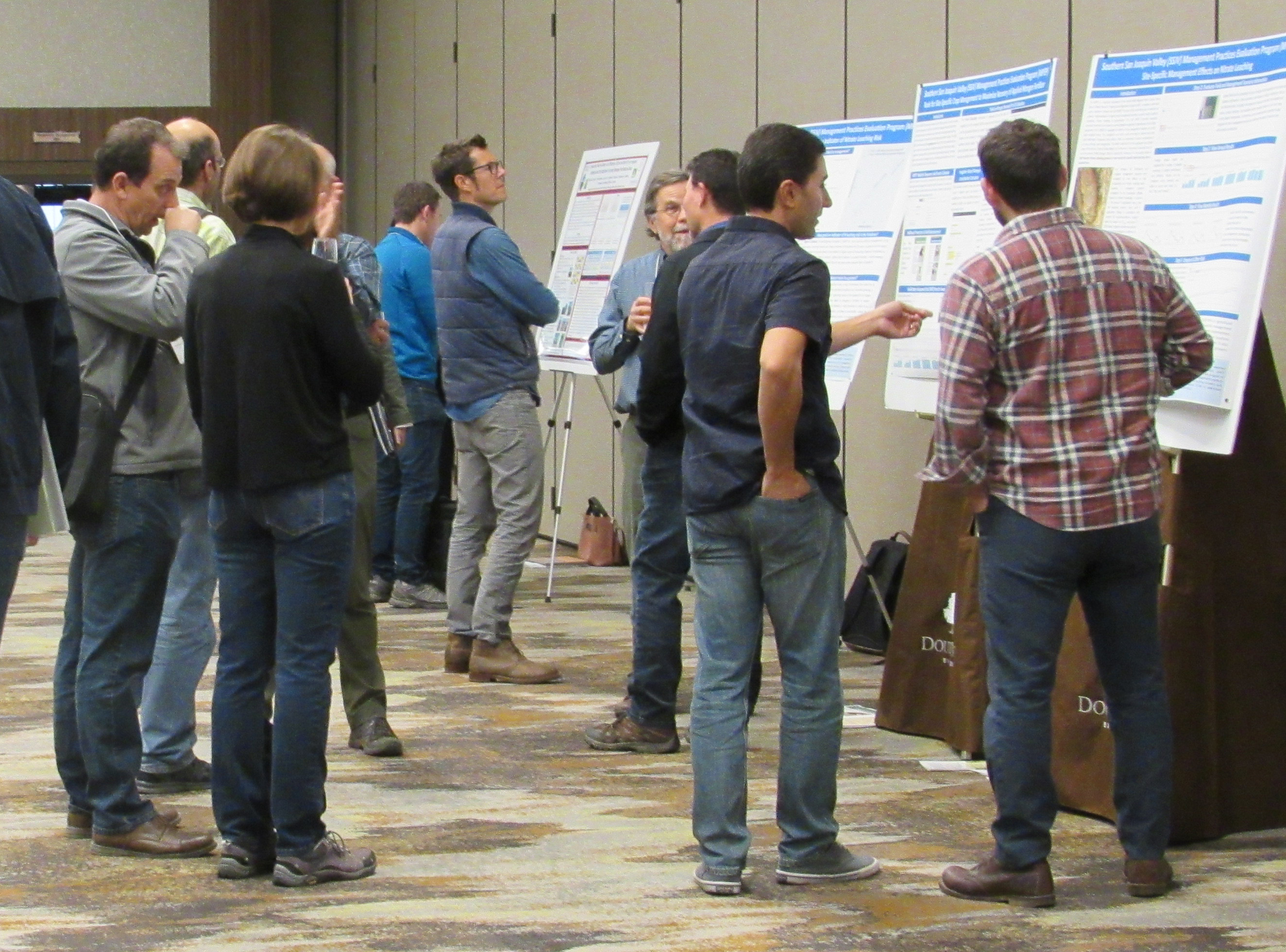 Conference attendees viewing posters and chatting.